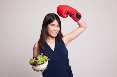 Genç Asyalı kadın boks eldiven ve salata ile.