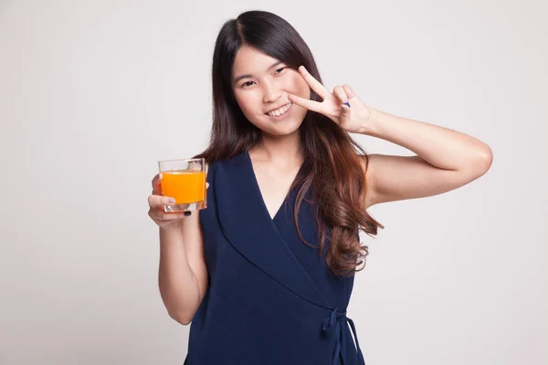 Ung asiatisk kvinna Visa seger tecken drink apelsin juice. — Stockfoto