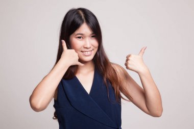 Genç Asyalı kadın başparmak telefon jest ile göstermek yukarıya.