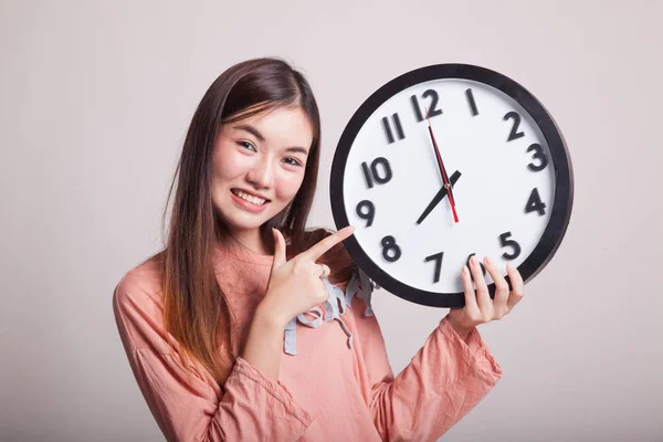 Joven asiática mujer punto a un reloj . — Foto de Stock