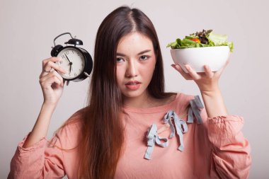 Saat ve salata ile genç Asyalı kadın.