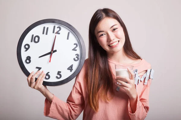 Friska asiatisk kvinna dricksglas mjölk håller klockan. — Stockfoto