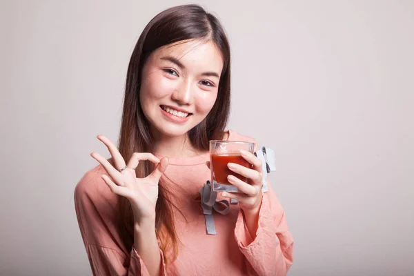 Νεαρή γυναίκα της Ασίας δείχνουν Ok με χυμό ντομάτας. — Φωτογραφία Αρχείου