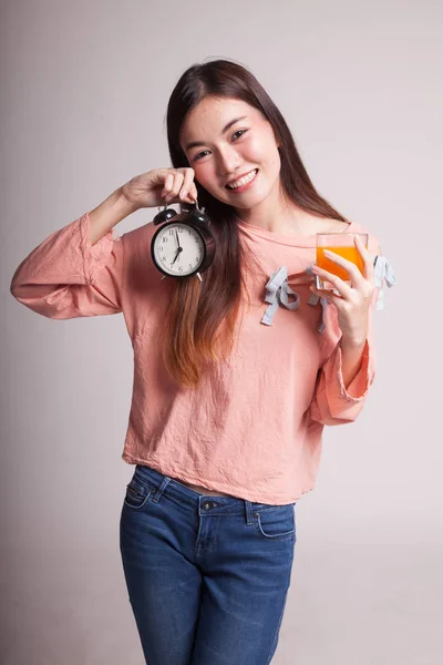 Aziatische vrouw met een klok drankje oranje sap. — Stockfoto