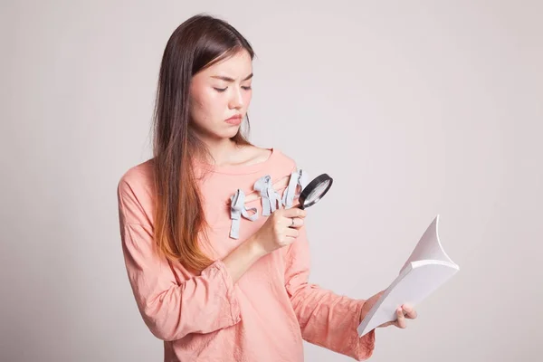 Aziatische vrouw met een boek en vergrootglas. — Stockfoto