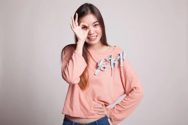 Vacker ung asiatisk kvinna Visa Ok skriva över hennes öga. — Stockfoto