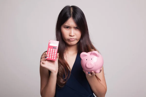 Unhappy Asian woman with calculator and piggy bank. — Stock Photo, Image