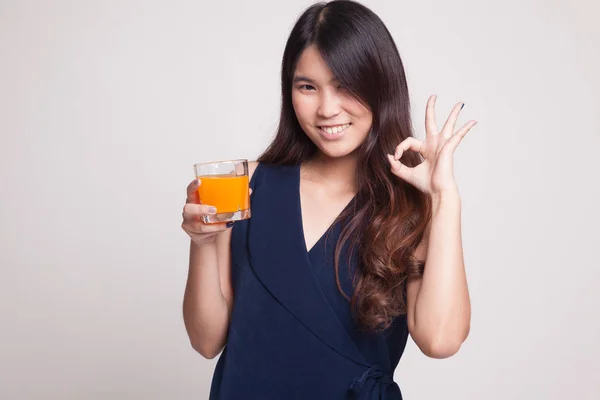 Joven mujer asiática beber jugo de naranja mostrar OK signo . — Foto de Stock