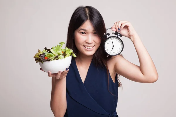 Ung asiatisk kvinna med klocka och sallad. — Stockfoto