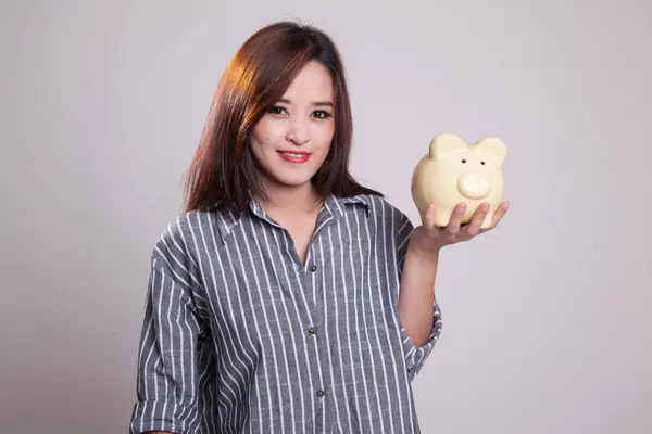 Jovem mulher asiática com um banco de moedas de porco . — Fotografia de Stock