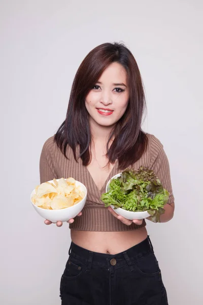 Junge Asiatin mit Kartoffelchips und Salat. — Stockfoto
