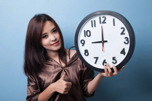 Young Asian woman thumbs up with a clock.