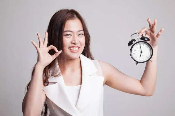 Jeune asiatique femme montrer OK avec une horloge . — Photo