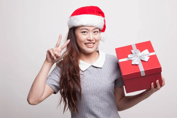 Mujer asiática joven muestra signo de victoria con una caja de regalo . —  Fotos de Stock