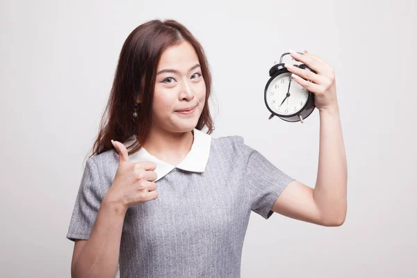 Young Asian woman show thumbs up with a clock. — Stock Photo, Image