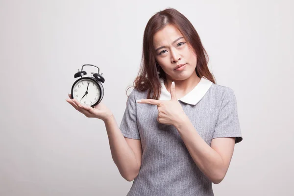 Wütende junge asiatische Frau zeigt auf eine Uhr. — Stockfoto