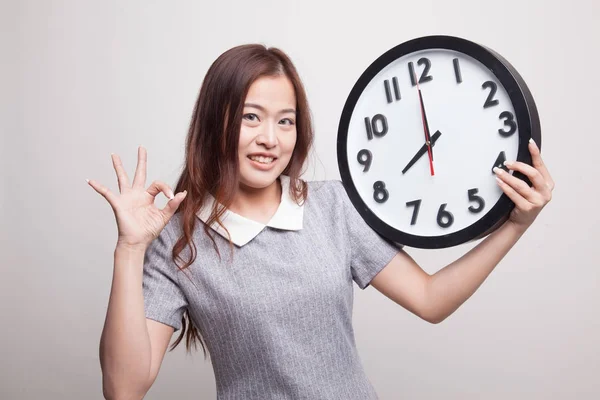 Junge asiatische Frau zeigen ok mit einer Uhr. — Stockfoto