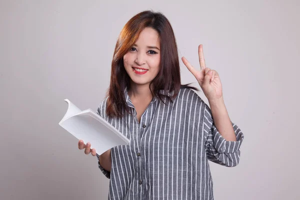 Młoda kobieta azjatyckich Pokaż victor znak z książką. — Zdjęcie stockowe