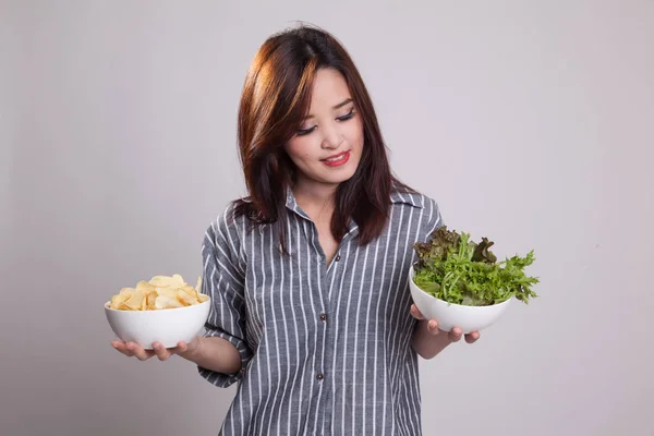 Ung asiatisk kvinna med potatischips och sallad. — Stockfoto