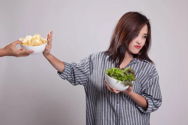 Ung asiatisk kvinna med sallad säga nej till potatischips. — Stockfoto