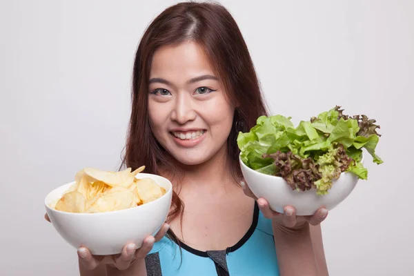 Mooie Aziatische gezond meisje salade en aardappels, chips. — Stockfoto