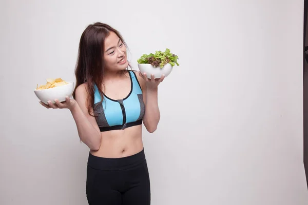 Schöne asiatische gesunde Mädchen Salat und Kartoffelchips. — Stockfoto