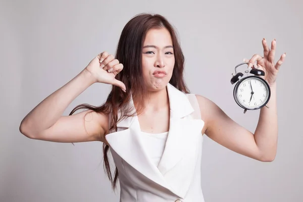Young Asian woman thumbs down with a clock. — Stock Photo, Image
