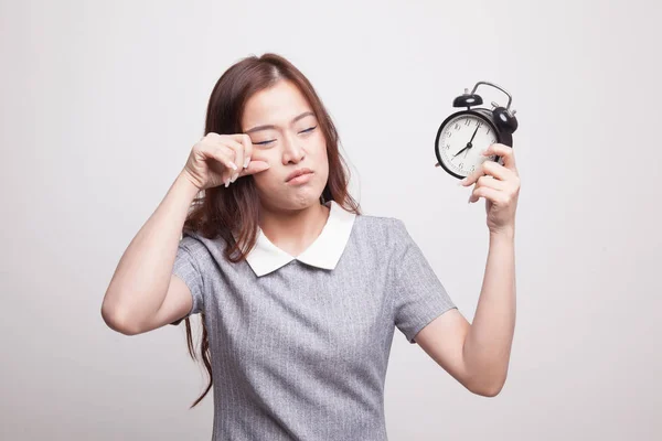 Schläfrige junge asiatische Frau mit einer Uhr am Morgen. — Stockfoto