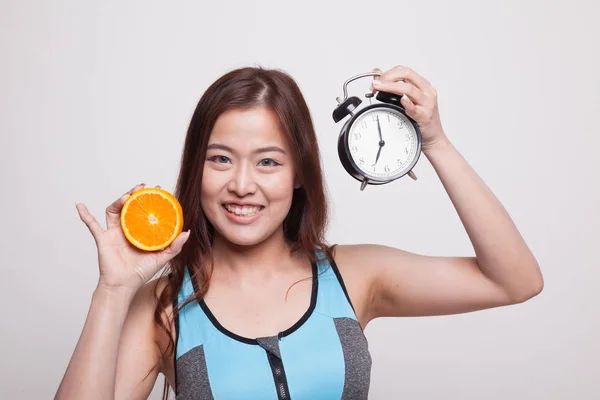 Mooie Aziatische gezond meisje met sinaasappel en klok. — Stockfoto