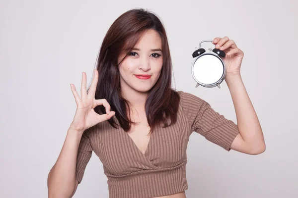 Young Asian woman show OK with a clock. — Stock Photo, Image