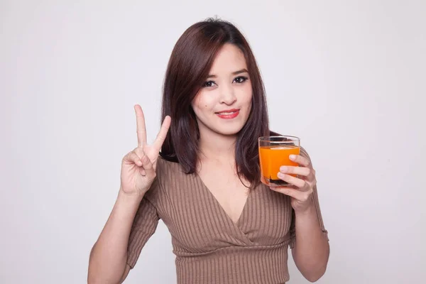 Молодая азиатка показывает знак победы напиток апельсиновый сок . — стоковое фото