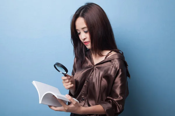 Femme asiatique avec un livre et une loupe . — Photo