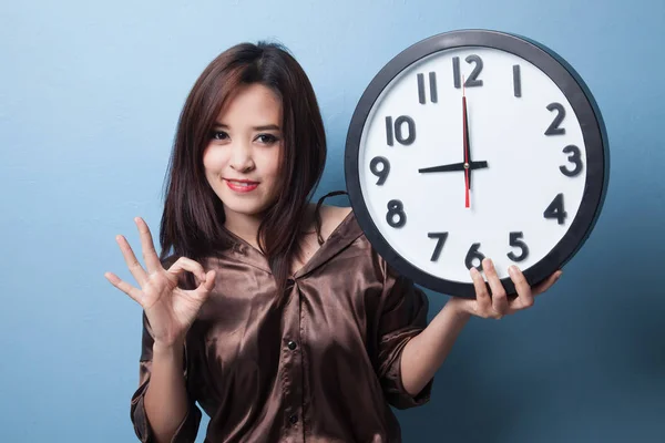 Jeune asiatique femme montrer OK avec une horloge . — Photo