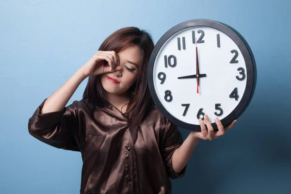 Sleepy jonge Aziatische vrouw met een klok in de ochtend. — Stockfoto