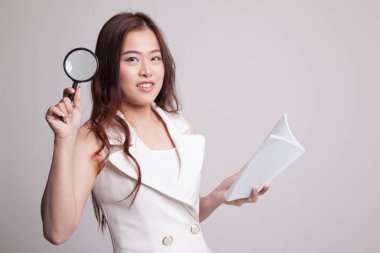 Bir kitap ve Büyüteç ile Asyalı kadın.