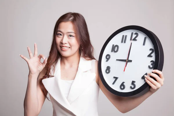 Young Asian woman show OK with a clock. — Stock Photo, Image