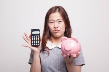 Hesap makinesi ve kumbara ile mutsuz Asyalı kadın.