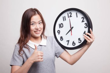 Genç Asyalı kadın başparmak yukarıya ile bir masa saati.