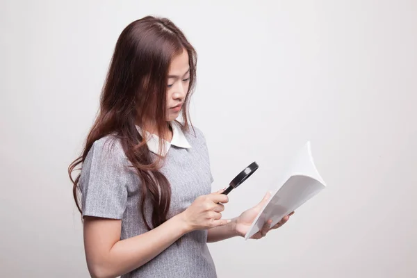 Asiatisk kvinna med en bok och förstoringsglas. — Stockfoto