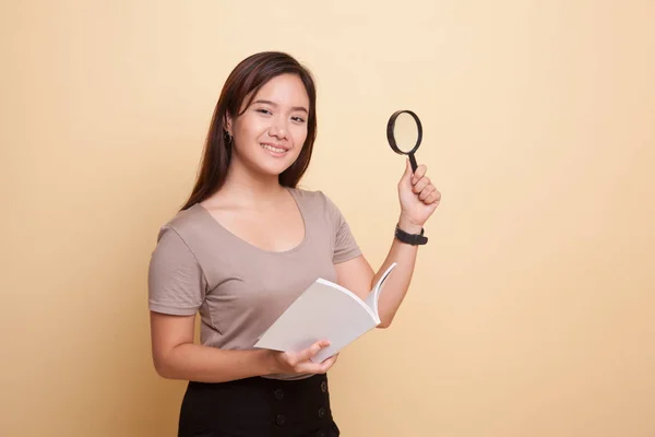Asian woman with a book and magnifying glass. — Stock Photo, Image
