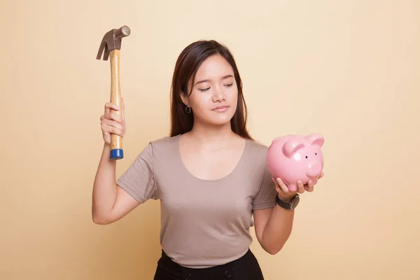 Asiatisk kvinna med gris mynt bank och hammare. — Stockfoto