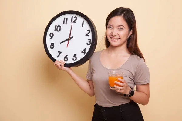 Mujer asiática con un reloj beber jugo de naranja . — Foto de Stock