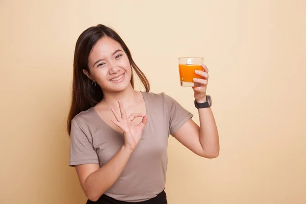 Jonge Aziatische vrouw Toon Ok drinken sinaasappelsap. — Stockfoto