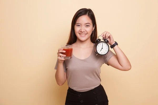 Ung asiatisk kvinne med tomatjuice og klokke . – stockfoto