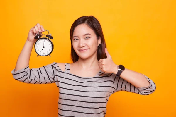 Genç Asyalı kadın ortaya başparmak ile bir saat. — Stok fotoğraf