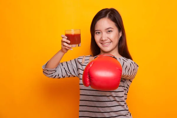 Giovane donna asiatica con succo di pomodoro e guanto da boxe . — Foto Stock