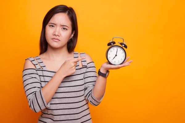 Wütende junge asiatische Frau zeigt auf eine Uhr. — Stockfoto