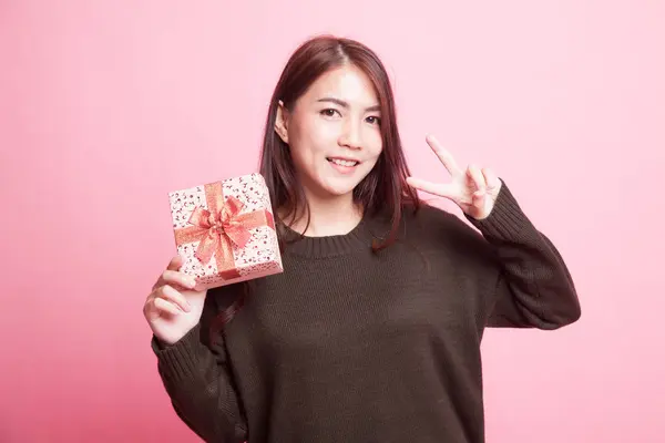 Молодая азиатка показывает знак Победы с подарочной коробкой . — стоковое фото