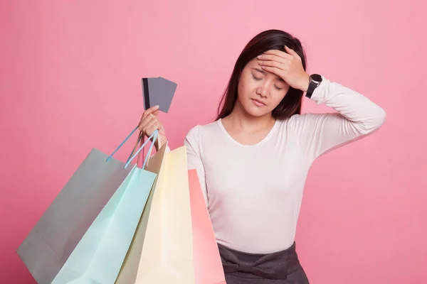 Ongelukkige jonge Aziatische vrouw met shopping tassen en credit card. — Stockfoto