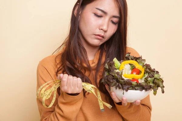 Unhappy Asian woman with measuring tape and salad. — Stock Photo, Image
